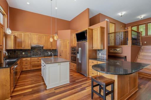 The kitchen features: a 13 ft ceiling w/6 recessed lights, 3 pendant lights, & 1 built-in speaker (next to the living room speaker); custom, maple cabinetry; slate tile backsplash, solid surface countertops; and Brazilian cherry hardwood floors.