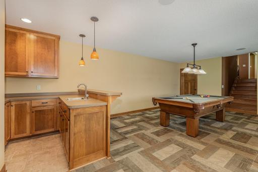 The family room has: an 8 ft knock down ceiling w/4 recessed lights & 4 speaker rough-ins. The door behind the pool table leads to the storage/mechanical room & crawl space area. There is zoned, in-floor heat for the ENTIRE basement level!