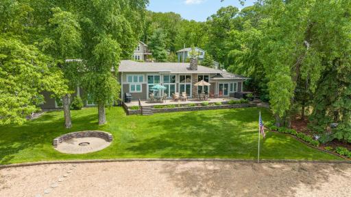 This aerial view shows: the meticulously landscaped backyard; the 60 foot!! tiered, paver patio; the custom, paver fire pit area; and the inviting 150' sandy beach.