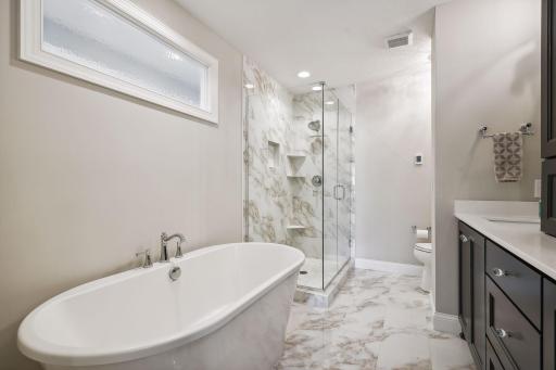 A freestanding soaking bathtub and tiled shower with glass enclosure complete the Primary Suite.