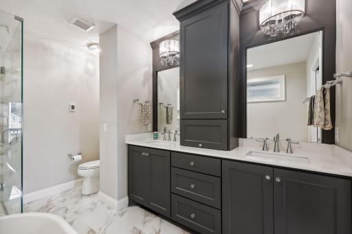 The luxurious Primary Bathroom features heated tile flooring and custom cabinetry with soft-close doors and drawers. The double vanity is topped with quartz and accented with designer fixtures.