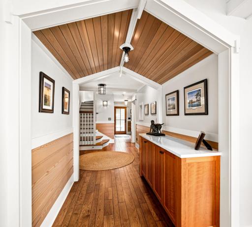 Main Level: Hallway features crafted ceiling of pickled wood and carpentry accents, built-in cherry cabinet with hand-crafted curved bench