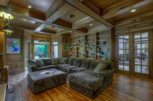 Warm and inviting library with box-beamed ceiling and fireplace.
