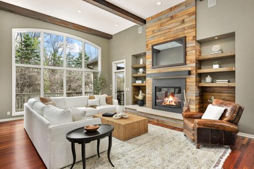 Custom Fireplace, stone hearth, and reclaimed wood mantle showcased through picturesque floor to ceiling arched windows!