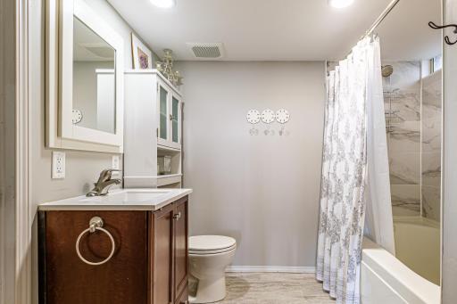Lower level bathroom features jacuzzi tub with marble tile surround.