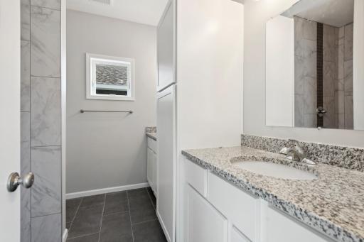 The owners bathroom includes a double vanity with beautiful white enameled cabinets, granite countertops, stunning walk-in tiled shower, and tiled floors. Photo of 4831 Education.