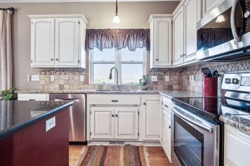 Elegant kitchen w/ Granite countertops, tiled backsplash, kitchen window, and stunning off white cabinetry.