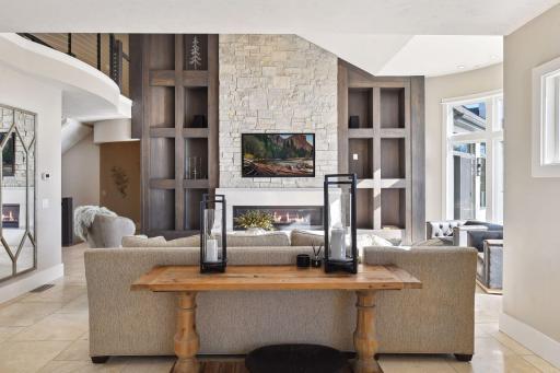 A sleek stone linear fireplace and custom surround create a cozy yet sophisticated ambiance perfect for relaxation and gatherings.