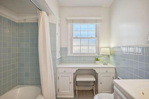 The pristine main-floor bathroom features original tile work and a makeup vanity.