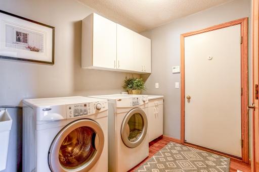 Main-floor laundry room with washer, dryer, sink, storage space, and a door leading to the garage.