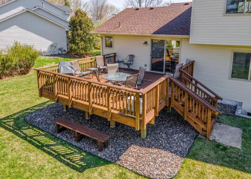 Spacious backyard with a large deck surrounded by mature trees and landscaping.