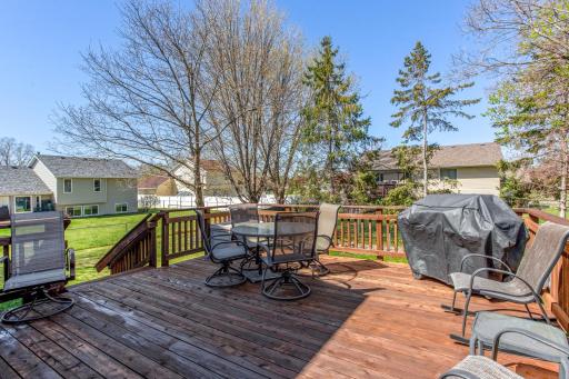 Spacious backyard with a large deck surrounded by mature trees and landscaping.