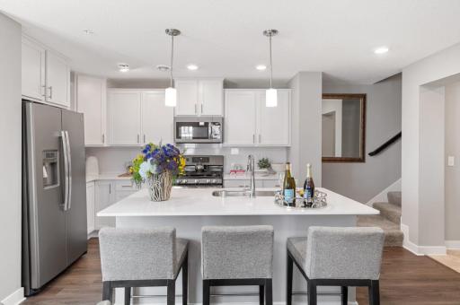 (Photo of decorated model, actual home's finishes vary) Welcome to your new home! This spacious kitchen features a large center island with quartz countertops, under mount sink, recessed lighting, LVP hardwood floors, stainless appliances and more!