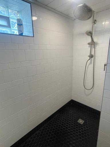 Fully tiled walk-in shower with rainhead and body spray.