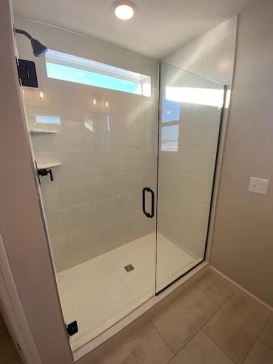 Fully Tiled Owner's Bath Shower with Solid Glass Frameless Shower Door