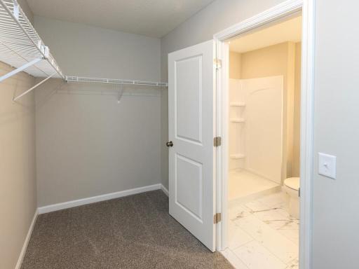 Primary Suite Walk In Closet. Photo taken of another home. Photos and renderings may not depict actual plan, materials, & finishes may vary. All measurements are approximate.