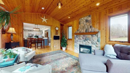 Sun-filled 4 Season Porch with cozy gas fireplace with stone surround and hardwood floors