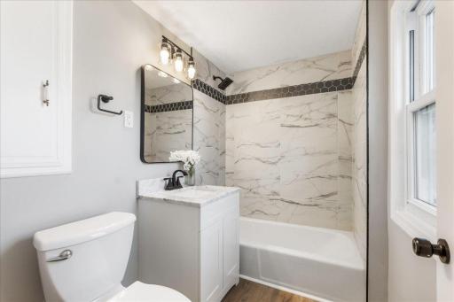 Step into luxury in this completely renovated upstairs bathroom, featuring stunning tile work, sleek fixtures, and natural light, truly a space of timeless beauty and modern convenience.