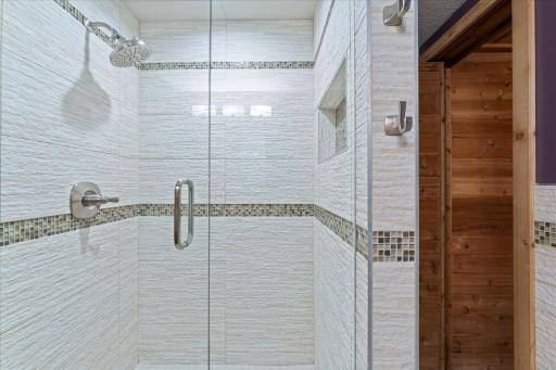 Lower level bathroom features walk-in tiled shower with glass door.jpg