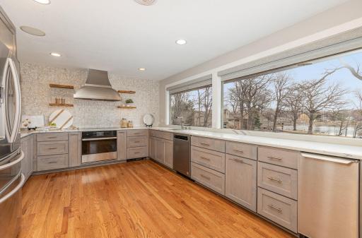 Upscale stainless steel appliances and Smart KitchenAid touchscreen cooktop and induction oven with decorative hood compliment the trendy grey shaker style kitchen cabinets.