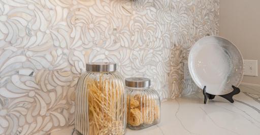 Close-up view of the exquisite and decorative tile work that runs the entire length of wall where the stove is located.