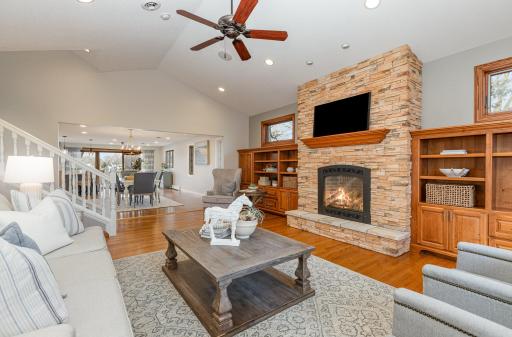 The main floor living room features floor to ceiling stone fireplace and built-in cabinetry that spans an entire wall with transom windows above.