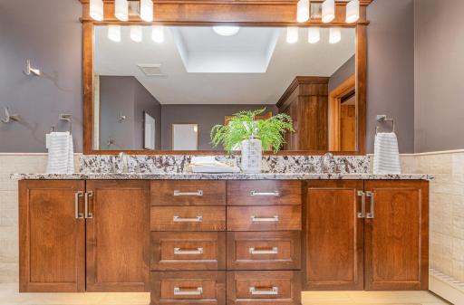 The large vanity in the primary bathroom has two sinks, a quartz counter, and under-cabinet lighting.