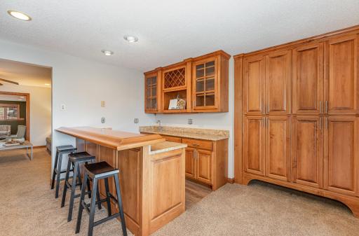 Lower-level bar area with sink and loads of custom, built-in cabinets for storage.