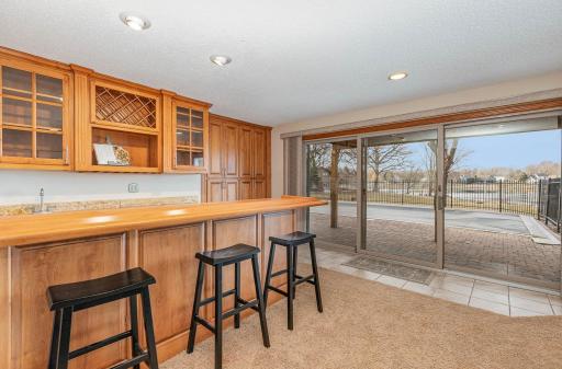 Lower-level bar and entertaining area has 3 panel sliding glass doors that open up to a heated in-ground pool with beautiful lake views.