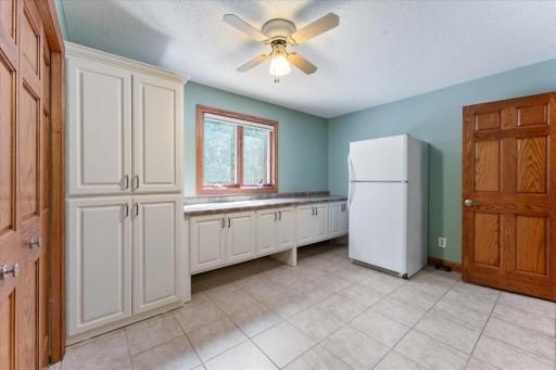 Spacious laundry room in lower level with a full wall of cabinets and folding counter.