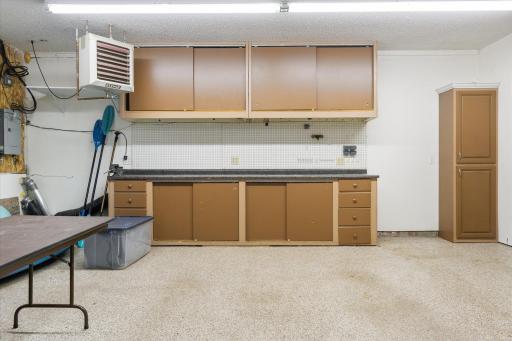 The insulated and heated garage has a work bench and storage cabinets. Also features a coated floor.