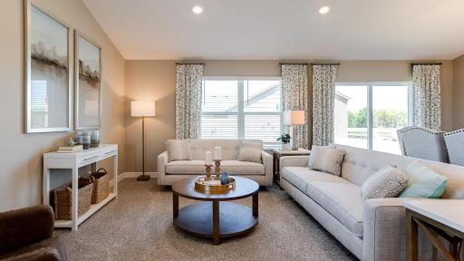 The living room-which serves as a cozy bookend to the area and highlights a space that's flooded in natural light via soaring windows overlooking the back of the home! Photo is of model home. Colors and options may vary. Ask Sales Agent for details.