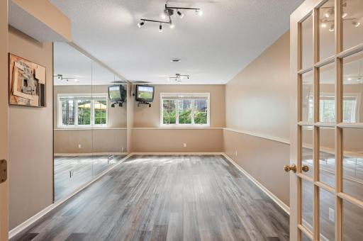 Another set of french doors lead to this inspiring exercise room with new LVP flooring. There is a spacious utility and storage room behind the mirrored wall.