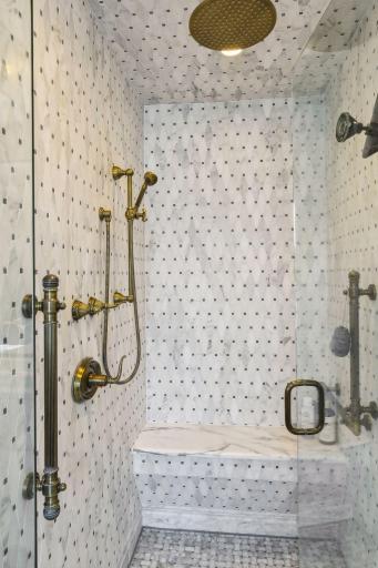 Oversized marbled shower in the primary bath has Phylich fixtures to include 10" rain shower head and separate high pressure hand shower.