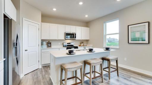 Bright and open kitchen with a fantastic island and large corner pantry! *Photo is of a model home, colors may vary in actual home.