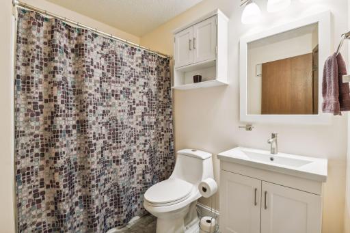 Remodeled bath with new toilet, vanity, lighting, professionally resurfaced tub and surround and vinyl tile floor.