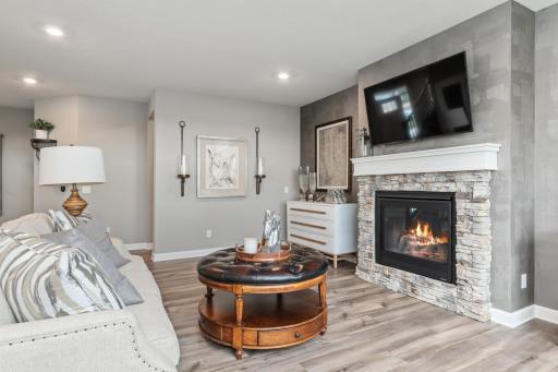(*Photo of decorated model, actual homes colors and finishes will vary) The modern fireplace with natural stone surround is an extraordinary room accent.