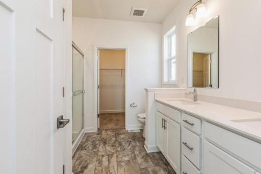 (Photo of actual home) The en-suite bathroom features a walk-in shower with glass enclosure and convenient shelving to store bathing essentials
