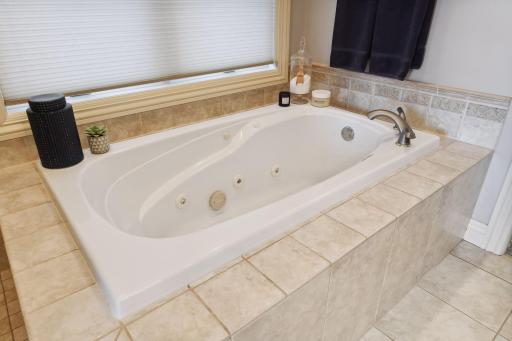 Large jetted soaking tub with ceramic tile surround.