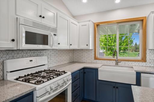 A close up view of the quartz counter top, ceramic backsplash and farmhouse sink.