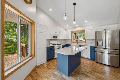 The kitchen has ample cabinet space, oak hardwood flooring, quartz counter top, and ceramic backsplash.