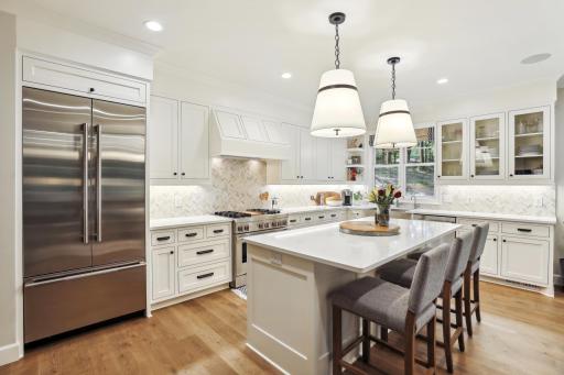 The kitchen showcases high-end stainless appliances, custom cabinetry, quartz counters and a walk-in pantry
