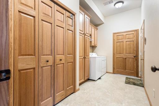 A spacious main floor laundry room boasts a large coat closet and additional storage cabinetry