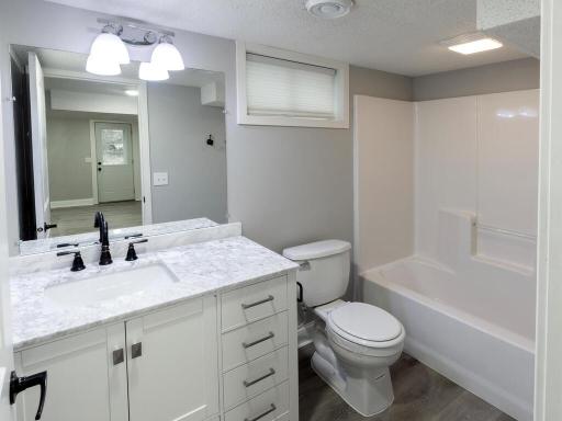 lower level full bath has an updated vanity, granite counter top and plumbing fixtures