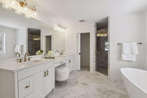 Spa-like primary bathroom with custom shower, soaking tub, and heated marble floors. Photos are from a previously built home.