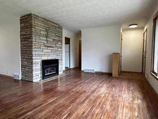 Living area includes a gas limestone fireplace and original hardwood flooring.
