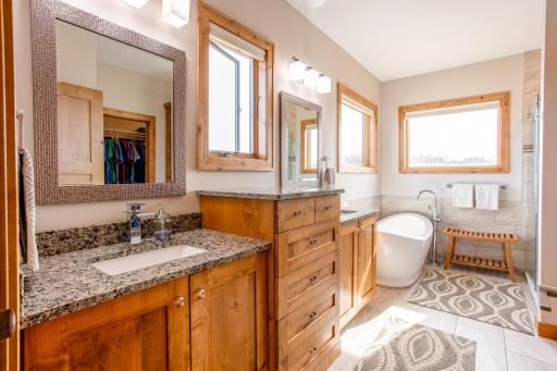 Tray vaulted master suite featuring a private master bathroom with dual sink vanities, a luxurious soaking tub, a walk-in tile shower, and a large walk-in closet.