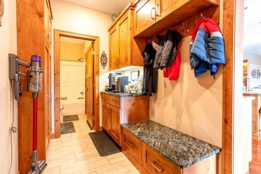 Main-floor mudroom with large coat closet, coat rack, and boot bench.
