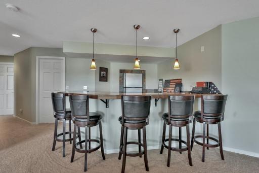 Family room wet bar with granite tops, refrigerator, small dishwasher and pendant lighting.