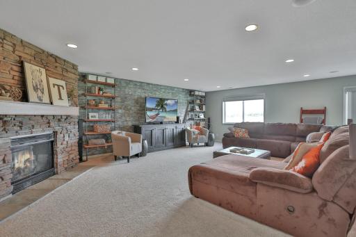 Lower level family room with corner fireplace, recessed lighting, decorative natural distressed wood feature.
